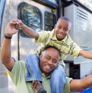 Happy Father and Son In Front of Their Beautiful RV At The Campground.